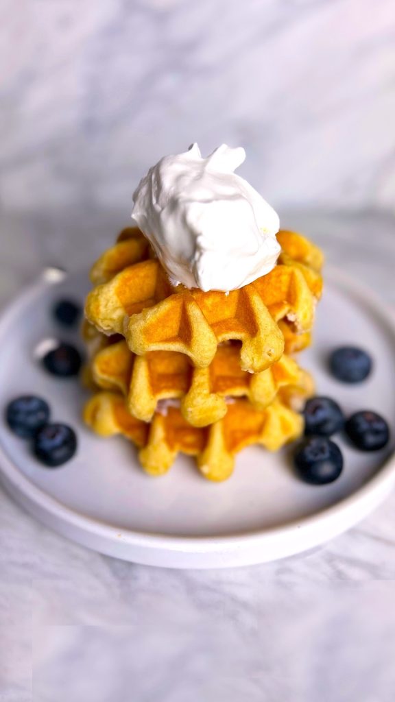 Whipped cream dollop on a stack of waffles with blueberries.